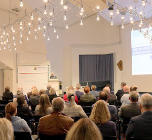 Frau am Rednerpult vor einer Gruppe Personen