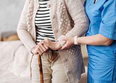 Pflegerin stützt ältere Frau