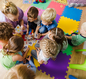 Kleinkinder mit erwachsener Person betrachten Karten mit Buchstaben