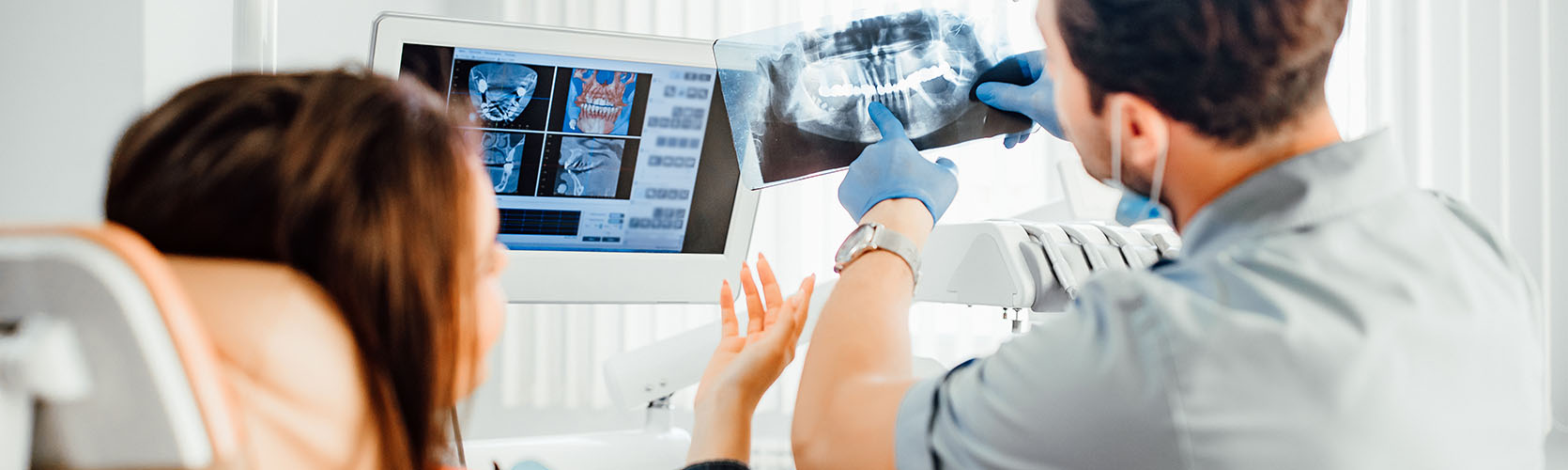 Medicine, dentistry and healthcare concept, male dentist showing teeth x-ray to female patient at dental clinic office.