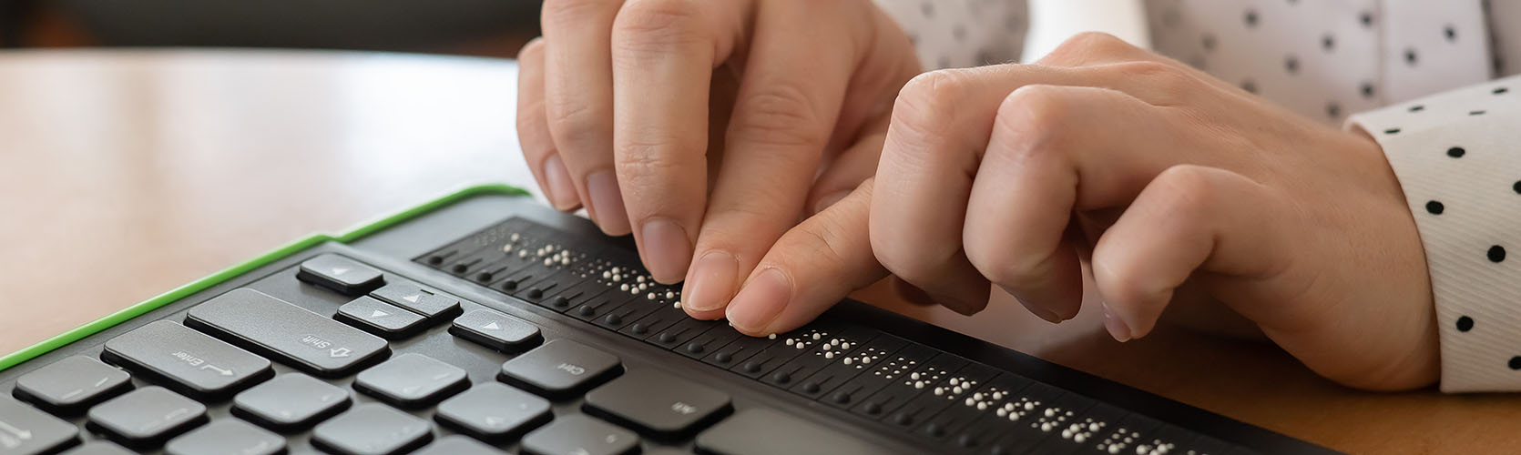 Eine blinde Frau nutzt einen Computer mit Braillezeile