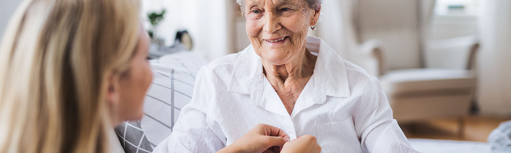 Pflegerin hilft Seniorin beim Anziehen